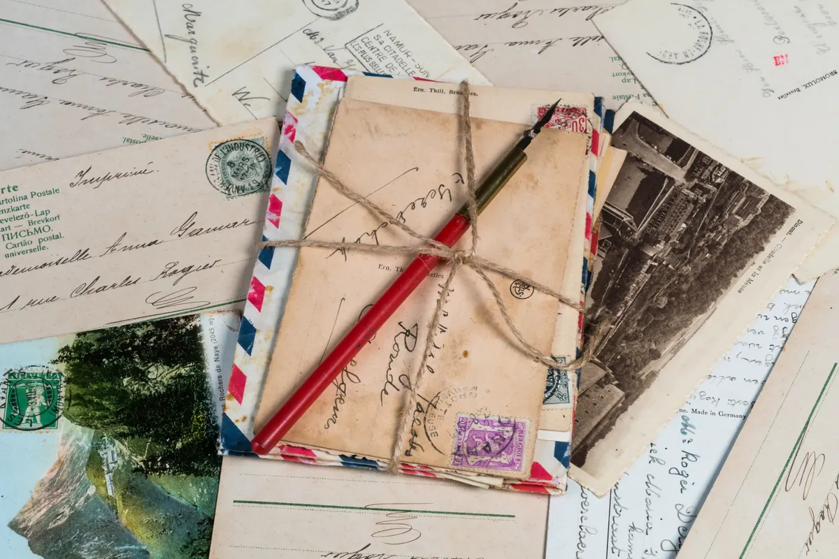 A new postcard collector organizing vintage cards at a wooden table with basic supplies.