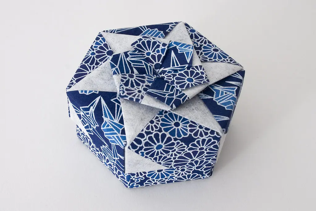 An intricate advanced origami sculpture featuring complex geometric folds and precise creases on a clean table.