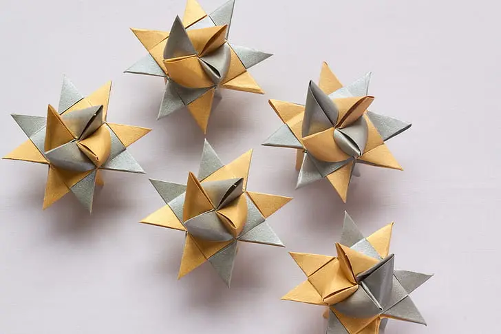 Close up of hands practicing early intermediate paper folding techniques carefully.
