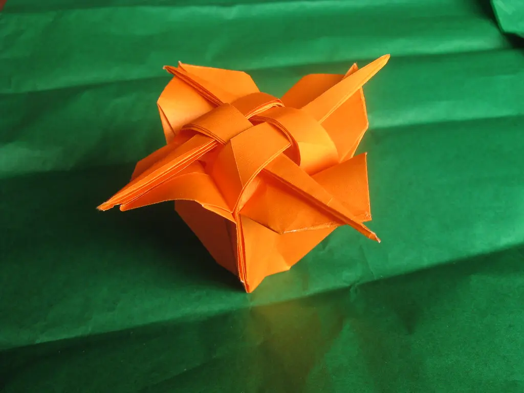Close-up of a beginner carefully folding thin kami paper during an origami project.