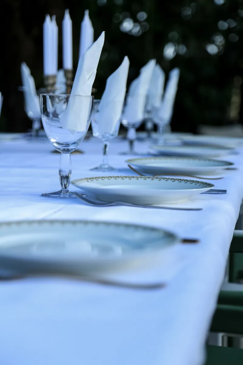 Elaborate European paper and linen napkin folding arranged in traditional geometric dinner table shapes.