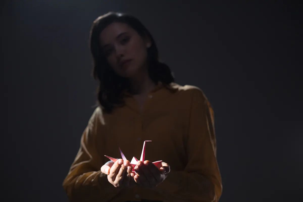 Hands carefully executing a complex fold during the middle stages of a paper crane.