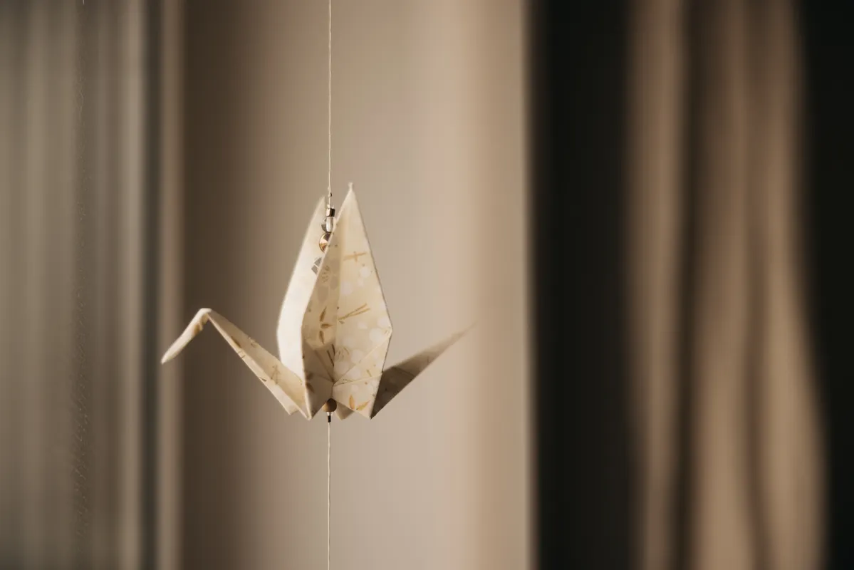 Close up of a folded paper crane showing thin layers and crisp creases on lightweight paper.