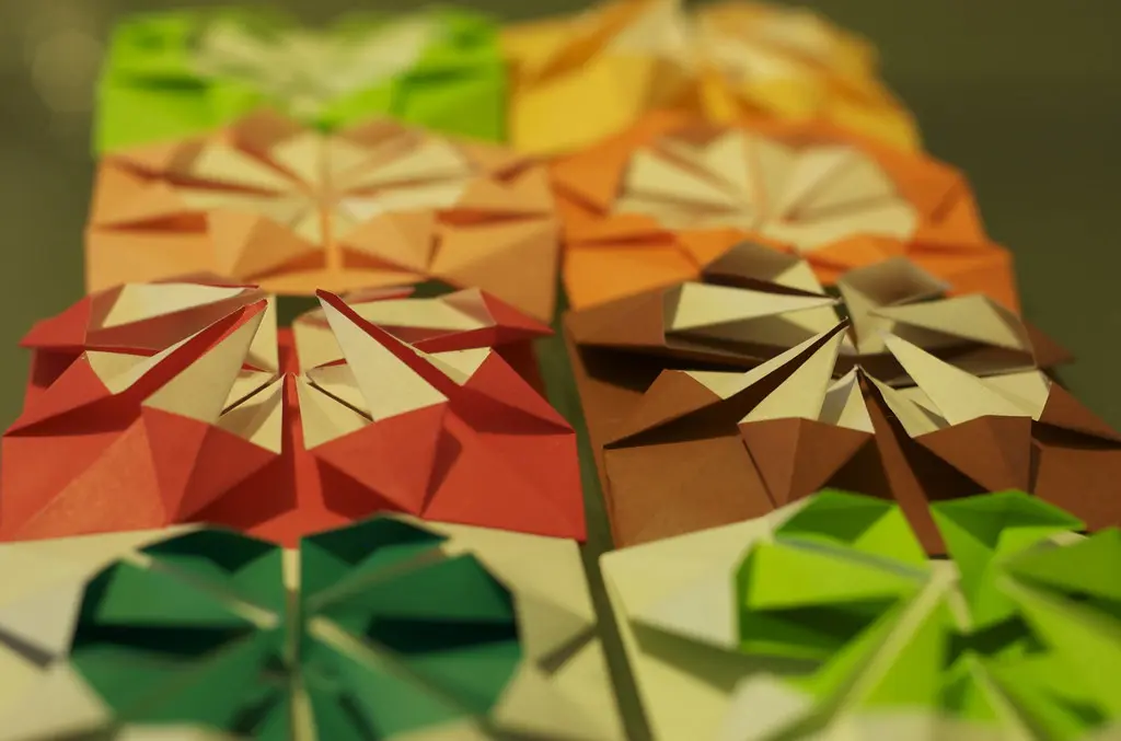 A finished modular geometric paper star next to a traditional single-sheet crane model.