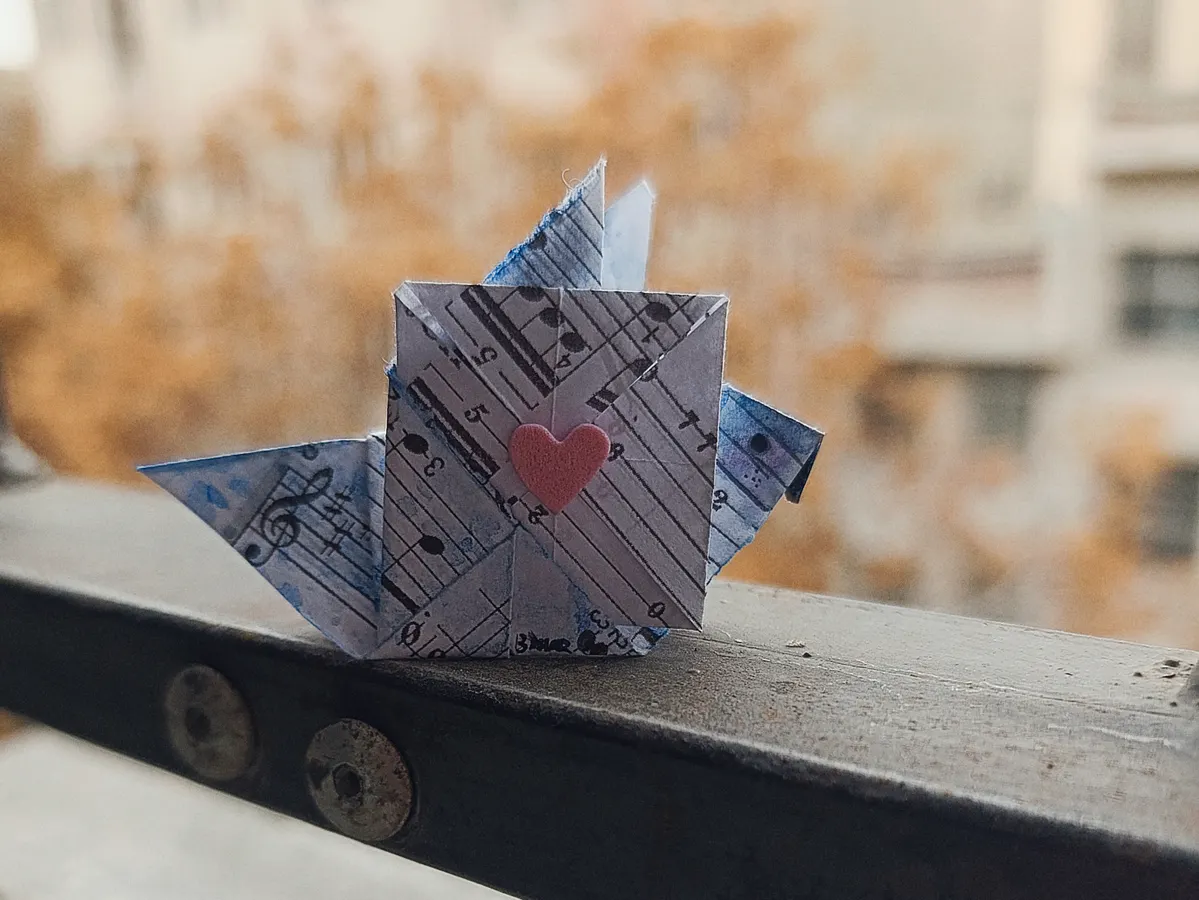 A crisp, folded paper crane sits on a flat surface representing the relaxing hobby of origami.