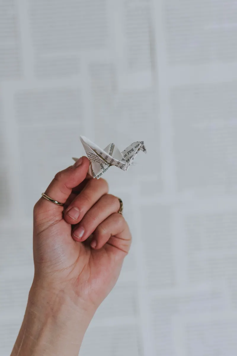 Hand folding a paper crane using a traditional origami diagram with zero written instructions.
