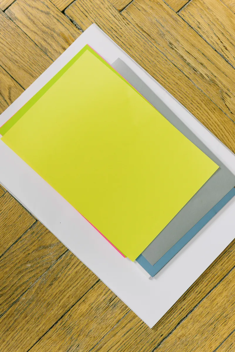 Organized tray with a bone folder and tweezers next to colorful origami paper.