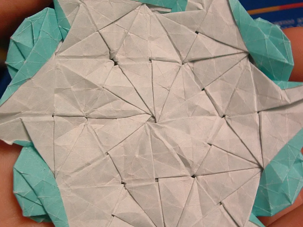 A close-up view of hands demonstrating the basic mechanics of an origami reverse fold.