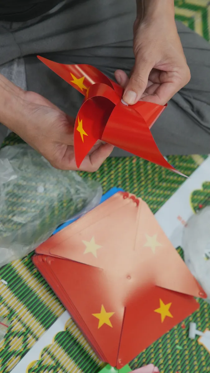 Hands folding a piece of scrap paper to practice the three steps of a petal fold.
