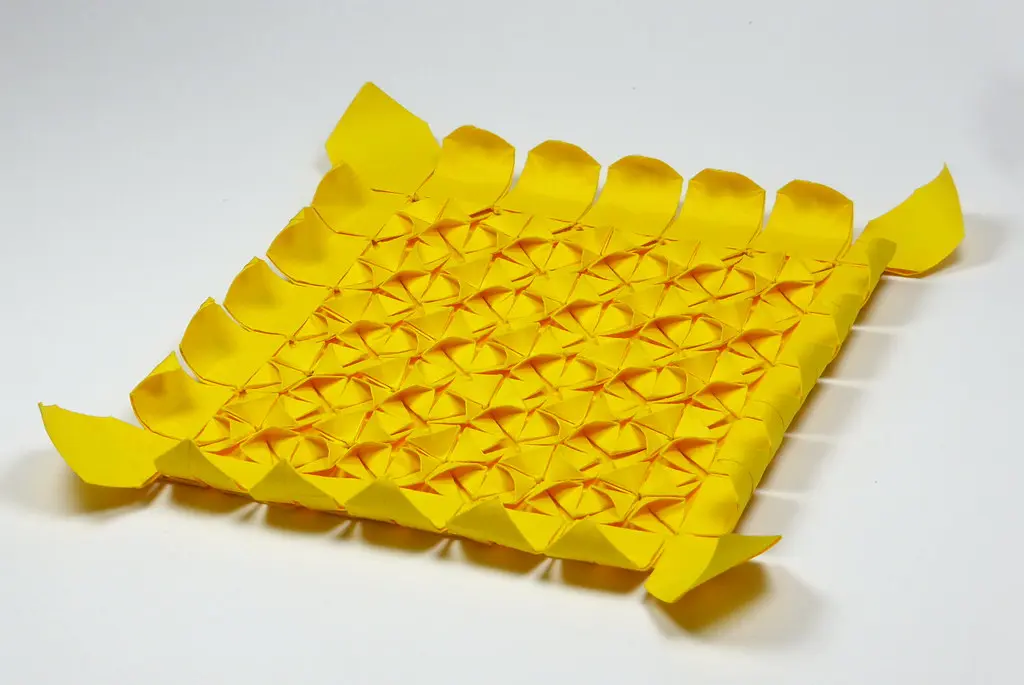 Close-up view of a complex single sheet origami tessellation featuring repeating geometric pleats and twists.