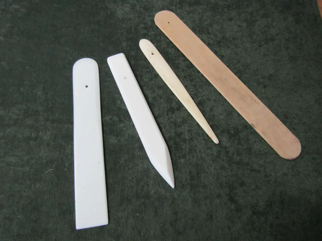 Using a bone folder tool to sharpen paper creases safely during origami assembly.